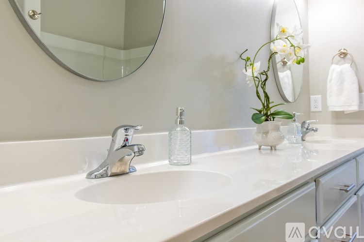 A white sink with a silver faucet and a round mirror above it.