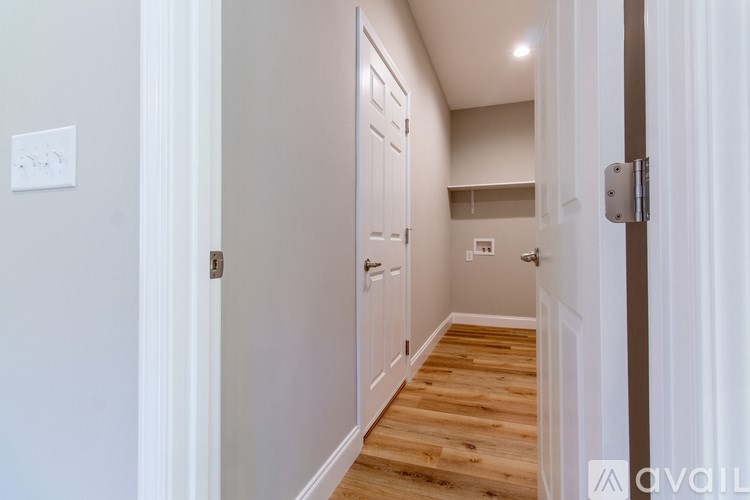 A hallway with a wooden floor and white walls.