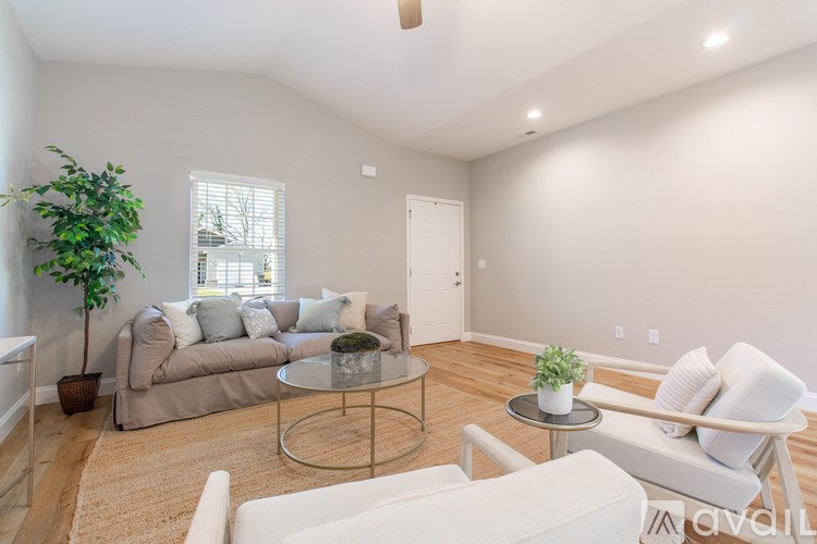 A living room with a couch, chair, and potted plant.