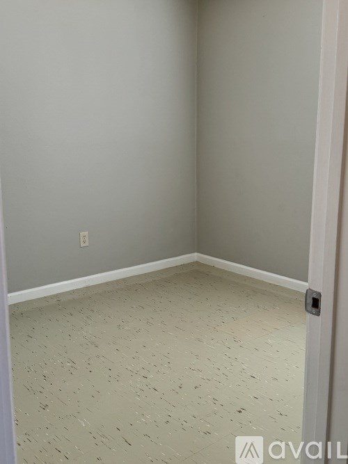 A room with a door and a light switch on the wall.