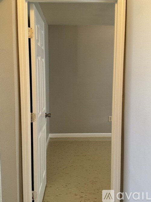 A white door is open to a room with beige walls.