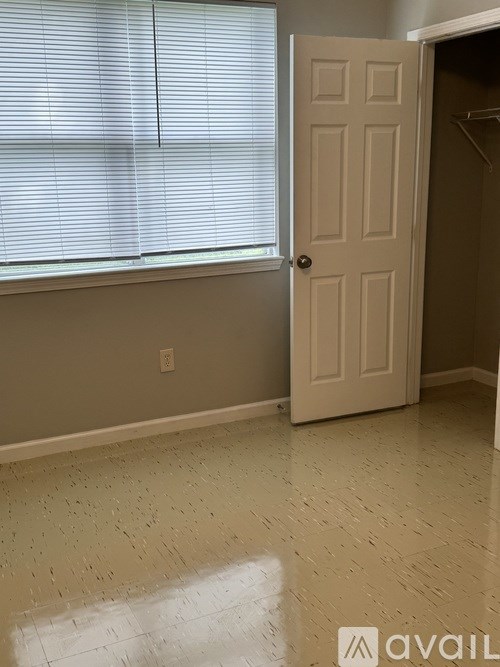 A room with a door and a window with blinds.