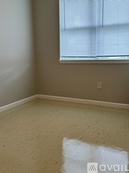 A room with a window and a wooden floor.