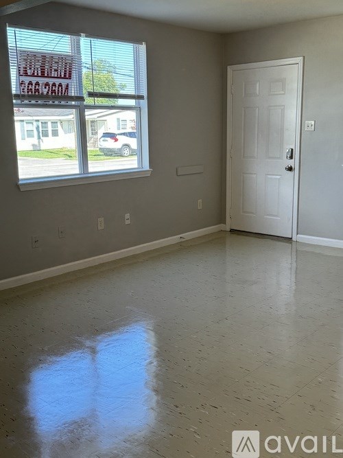 A room with a white door and a window showing a street view.