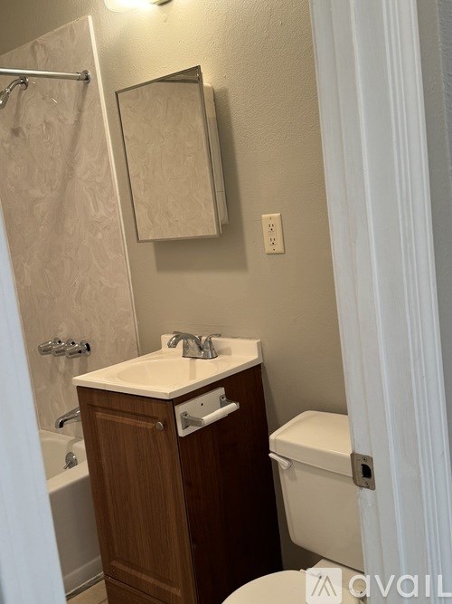 A bathroom with a toilet, sink, and mirror.