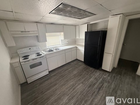 A small kitchen with a black fridge and white appliances.