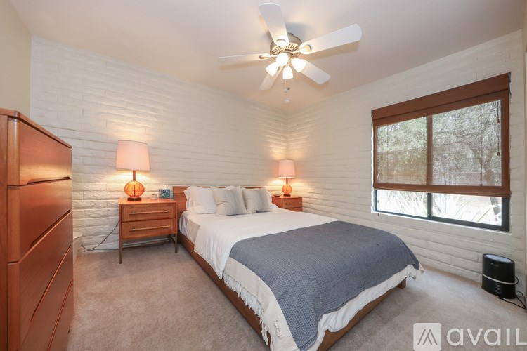 A bedroom with a bed, nightstands, and a ceiling fan.