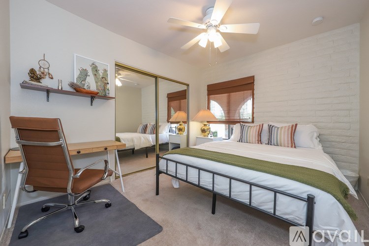 A bedroom with a bed, chair, and a ceiling fan.