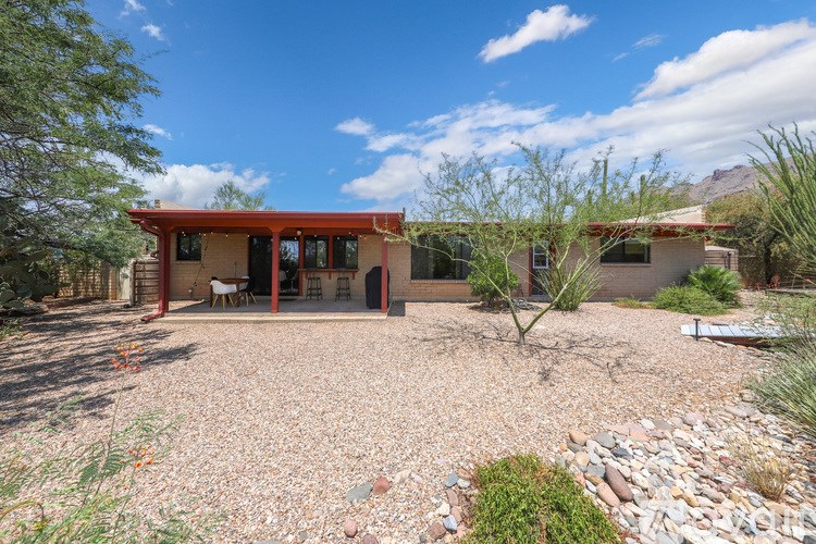 A house with a red roof and a gravel driveway.
