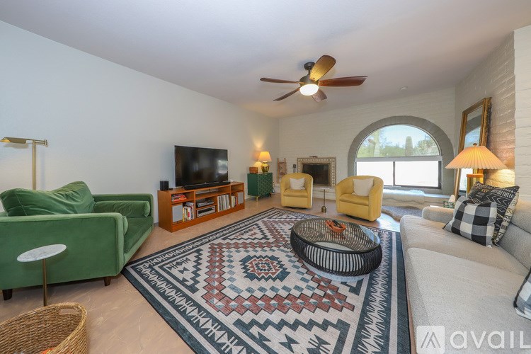 A living room with a green couch, a yellow chair, and a rug with a geometric pattern.