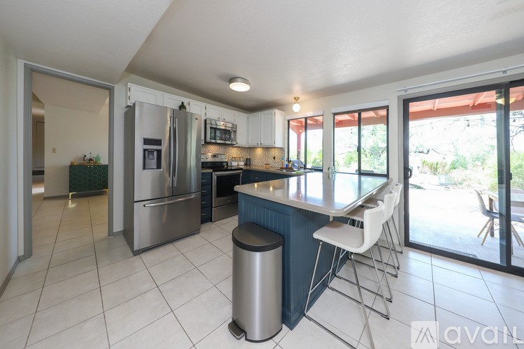 A kitchen with a bar stool and a trash bin.