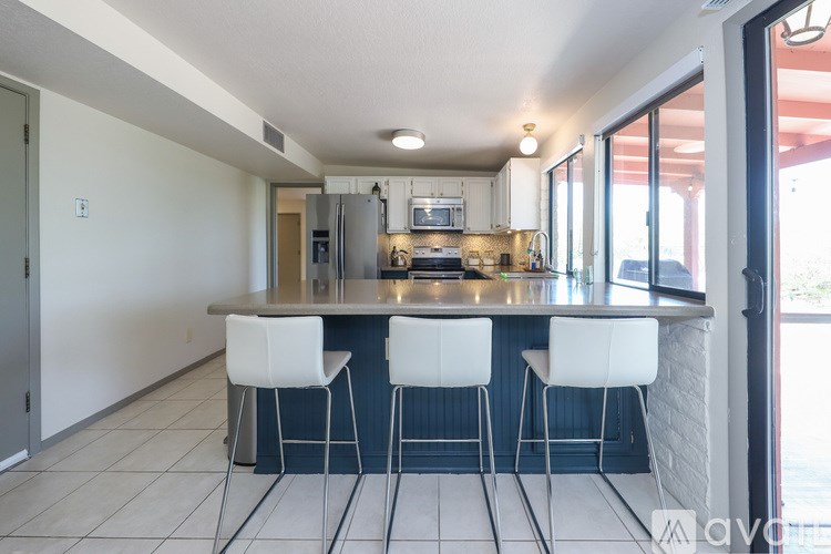 A kitchen with a bar area and white chairs.