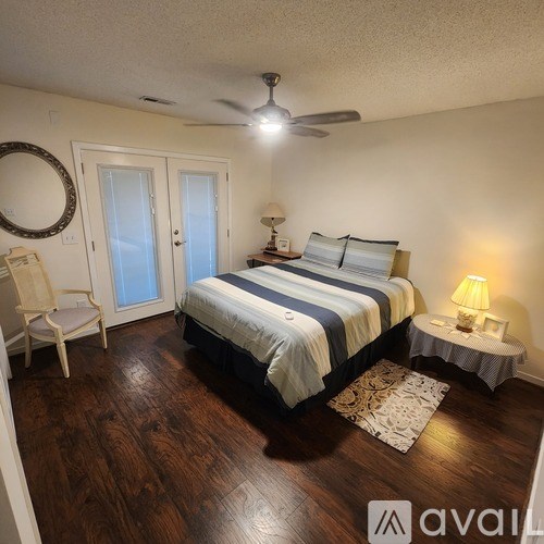 A bedroom with a bed, chair, and a ceiling fan.