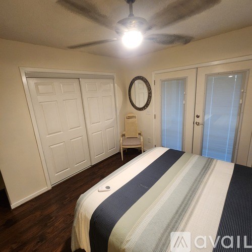 A bedroom with a bed, a chair, and a mirror.