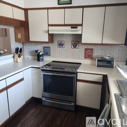 A kitchen with a stove top oven and white cabinets.