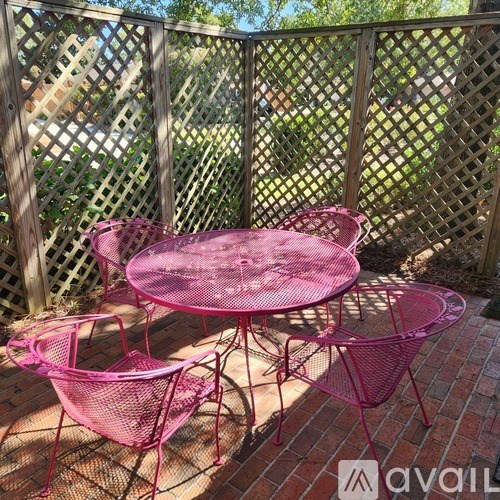 A pink table and chairs set on a patio.