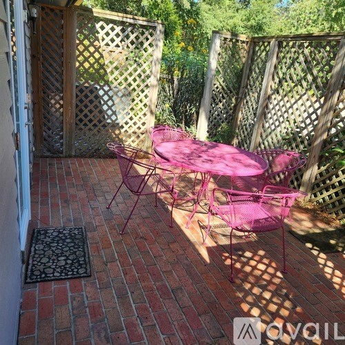 A patio with a pink table and chairs.
