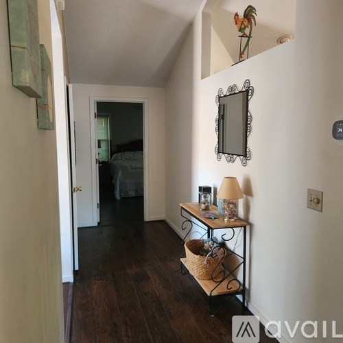 A hallway with a mirror and a table with a lamp on it.
