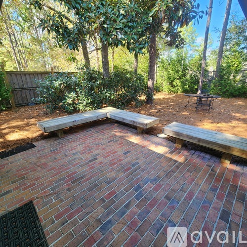 A patio with a bench and a table surrounded by trees.