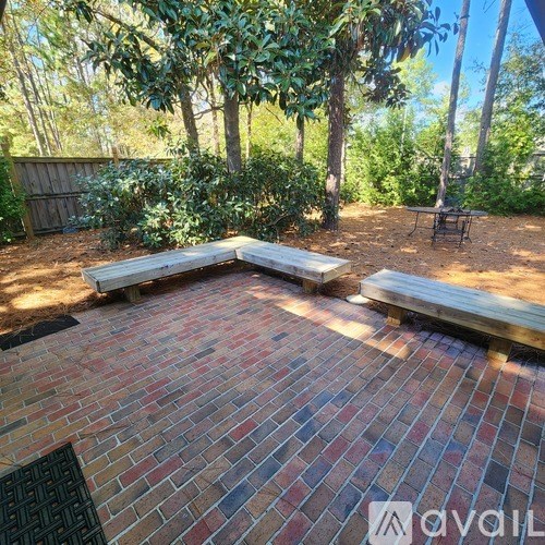 A patio with a bench and a table surrounded by trees.