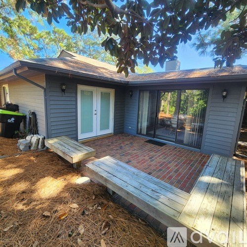A house with a grey siding and a white door is surrounded by trees.