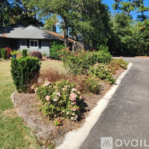 A house with a grey roof and a garden with pink flowers.