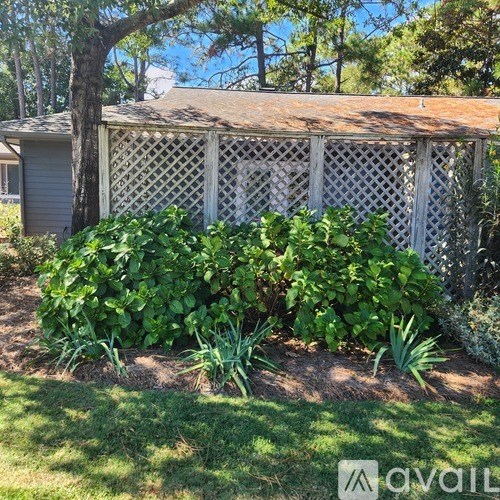 A small wooden building with a lattice fence and a sign that says "avail" in front of it.