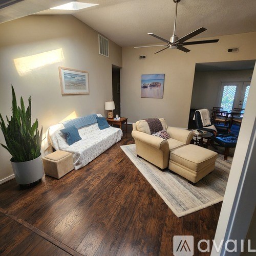 A living room with a white couch, a wooden floor, and a ceiling fan.