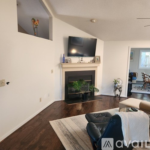 A living room with a fireplace and a television mounted above it.