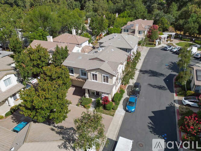A bird's eye view of a residential street with houses and parked cars.