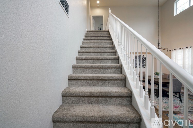 A staircase with a white railing and beige carpeted steps.