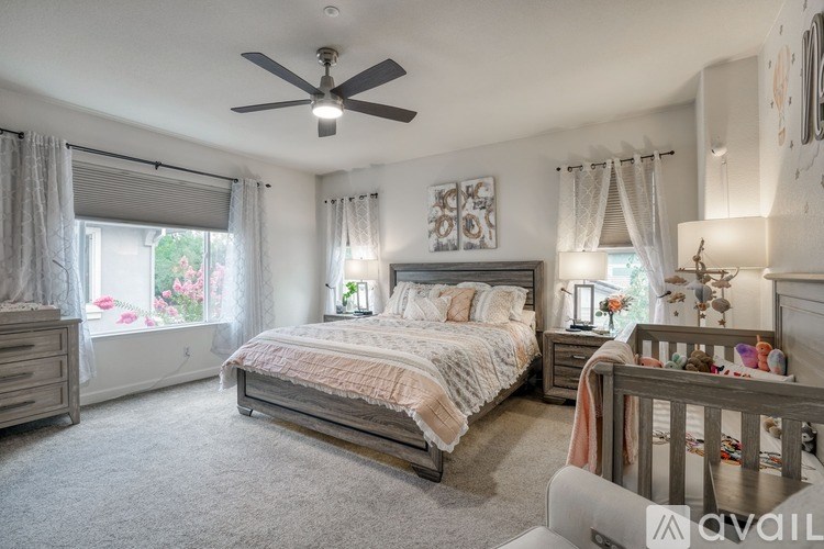 A well-lit bedroom with a large bed and a ceiling fan.