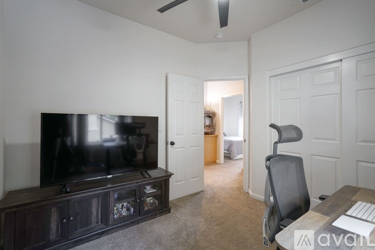 A room with a television, a chair, and a desk.