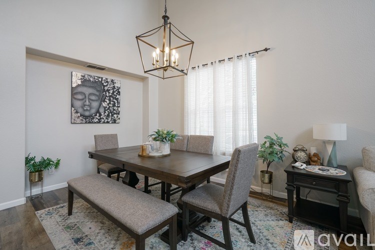 A dining room with a wooden table and chairs, a bench, and a chandelier.