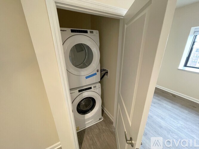 A white washing machine is in a small alcove in a room.