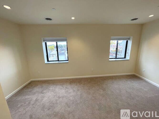 A room with two windows and carpeted floor.