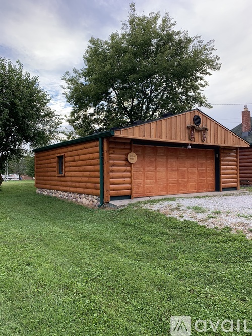 A wooden building with a green roof and a brown garage door.