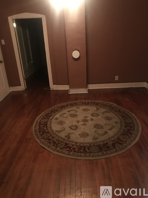A room with a rug on the floor and a doorway leading to another room.