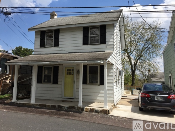 A two-story house with a yellow door and a car parked in front.