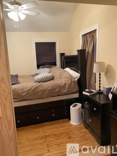 A bedroom with a bed, nightstand, and a ceiling fan.