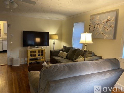 A living room with a grey couch and a television on the wall.