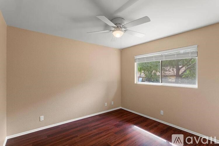 A room with a ceiling fan and a window showing an outdoor view.