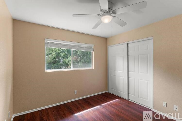 A room with a ceiling fan and a window with blinds.