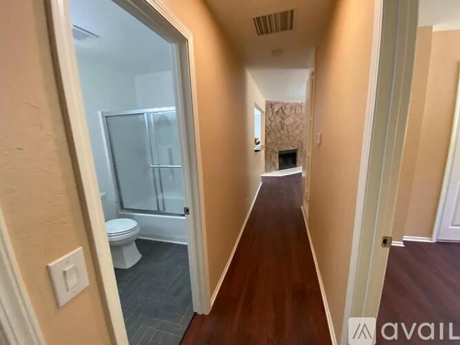 A long hallway with a toilet visible through the glass door.
