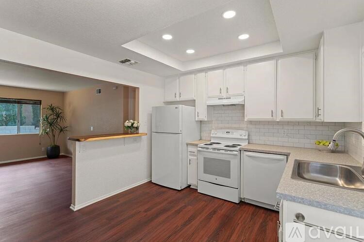 A kitchen with white appliances and wooden floors.