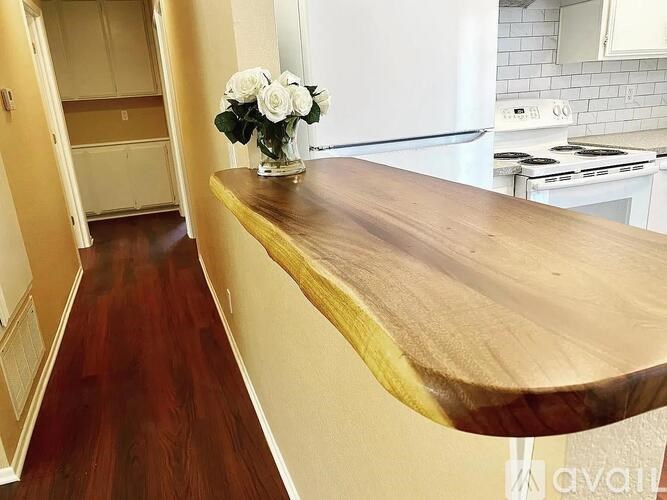 A kitchen with a wooden countertop and a vase of white flowers on it.