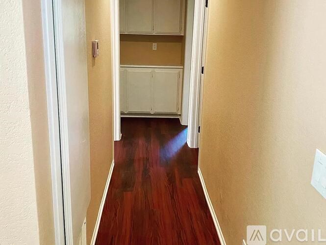 A hallway with wood flooring and white walls.