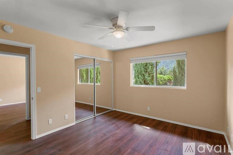 A room with a ceiling fan and sliding glass doors.