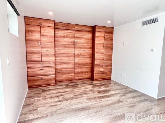 A room with wooden floors and a wall of wooden cabinets.