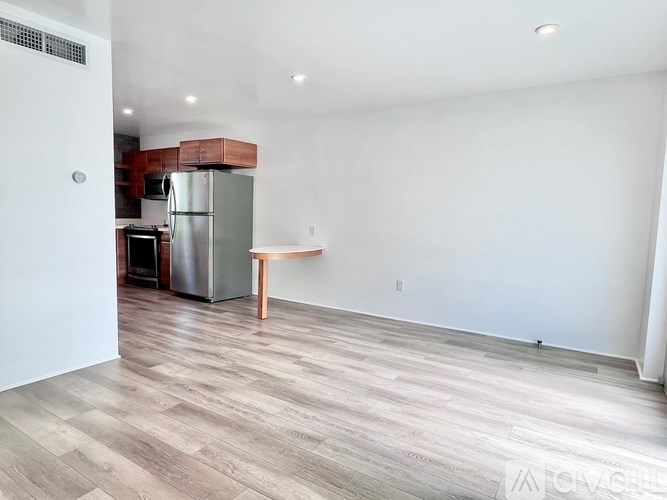 A kitchen with a refrigerator, microwave, and oven.